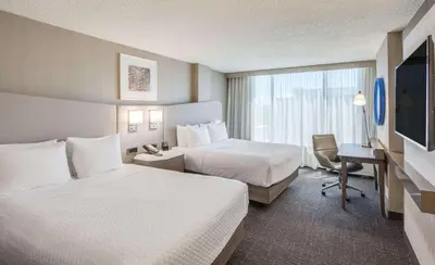 a hotel room with two beds and a desk at Sonesta Denver Downtown in Denver