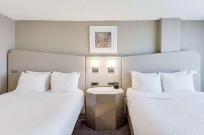 two beds in a hotel room with white pillows at Sonesta Denver Downtown in Denver