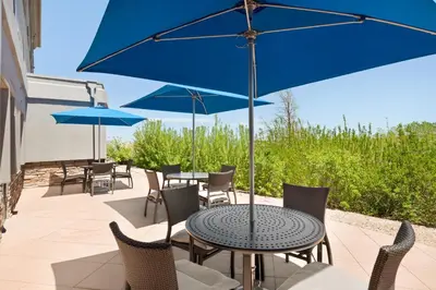 a patio with tables and chairs with blue umbrellas at Holiday Inn Express & Suites Denver Airport by IHG in Denver