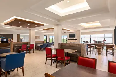 a dining room with tables and chairs and a cafeteria at Holiday Inn Express & Suites Denver Airport by IHG in Denver