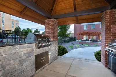 a patio with an outdoor kitchen with a brick wall at Staybridge Suites Denver International Airport by IHG in Denver