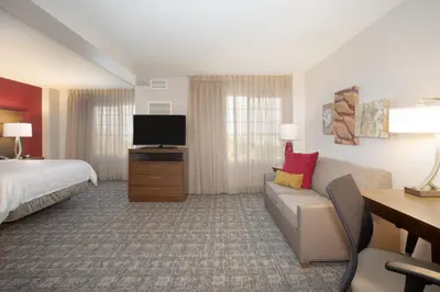 a hotel room with a bed and a couch and a tv at Staybridge Suites Denver International Airport by IHG in Denver