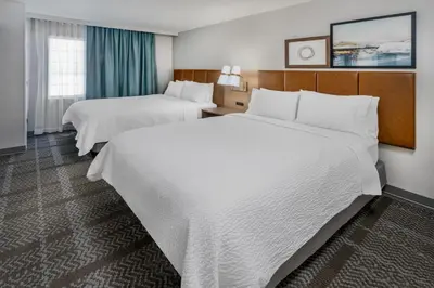 two beds in a hotel room with white sheets at Staybridge Suites Denver - Cherry Creek by IHG in Denver