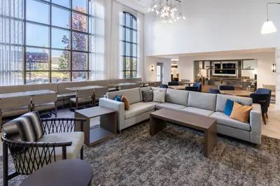 a living room with couches and tables and windows at Staybridge Suites Denver - Cherry Creek by IHG in Denver