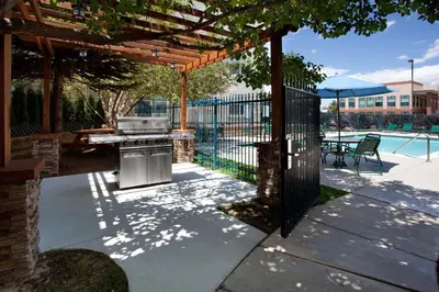 a barbecue under a wooden pergola next to a pool at Staybridge Suites Denver Tech Center by IHG in Centennial