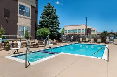 a swimming pool with chairs and a tree at Staybridge Suites Denver Tech Center by IHG in Centennial