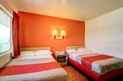 two beds in a room with an orange wall at Motel 6-Denver, CO - Airport in Denver