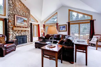 a living room with a couch and a stone fireplace at Keystone Private Homes by Vail Resorts in Keystone