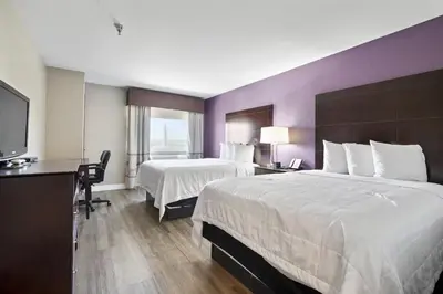 a hotel room with two beds and a flat screen tv at Baymont by Wyndham Henderson-Northeast Denver in Henderson