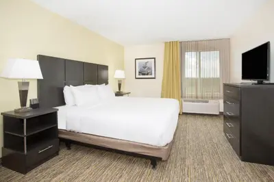 a hotel room with a bed and a flat screen tv at Candlewood Suites Longmont - Boulder Area by IHG in Longmont