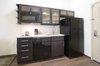 a kitchen with black cabinets and a black refrigerator at Candlewood Suites Longmont - Boulder Area by IHG in Longmont