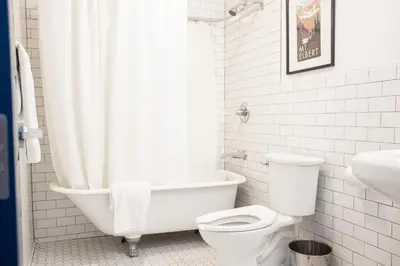a white bathroom with a tub and a toilet at 11th Avenue Hostel in Denver