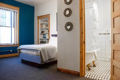 a bedroom with a bed and a bathroom with a shower at 11th Avenue Hostel in Denver