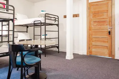 a room with bunk beds and a table and a door at 11th Avenue Hostel in Denver