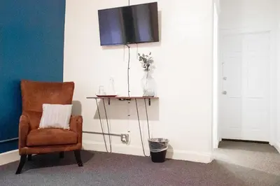 a room with a chair and a television on a wall at 11th Avenue Hostel in Denver