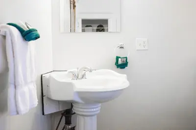 a white bathroom with a sink and a mirror at 11th Avenue Hostel in Denver