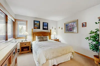 a bedroom with a bed and a desk and windows at Ski Run Condominiums 203 in Keystone