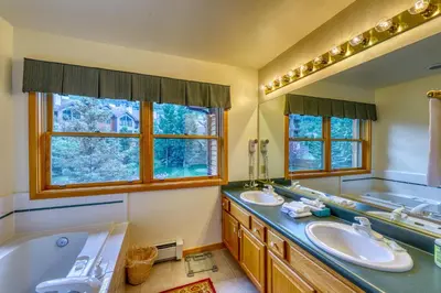 a bathroom with two sinks and a tub and two mirrors at Snake River Village 05 in Keystone