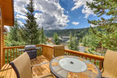 a deck with a table and chairs and a grill at Snake River Village 05 in Keystone