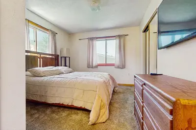 a bedroom with a bed and a dresser and windows at Snowdance Condo A101 in Keystone
