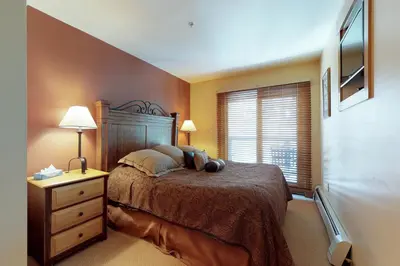 a bedroom with a bed and a dresser and a window at Springs Lodge 8888 in Keystone