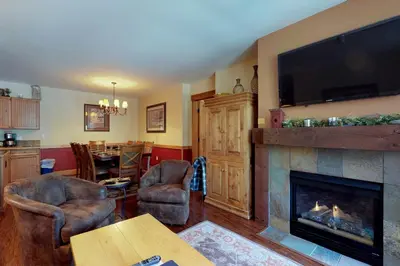 a living room with a fireplace and a flat screen tv at Springs Lodge 8888 in Keystone