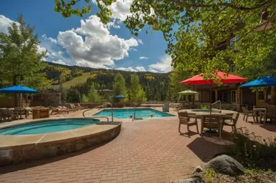 a swimming pool with tables and umbrellas in a resort at Trappers Crossing 8763 in Keystone
