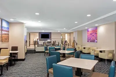 a restaurant with tables and chairs and a piano at La Quinta Inn & Suites by Wyndham Denver Aurora Medical in Aurora