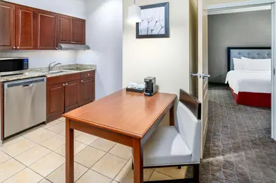 a kitchen with a table in a room with a bed at Homewood Suites by Hilton Denver - Littleton in Littleton