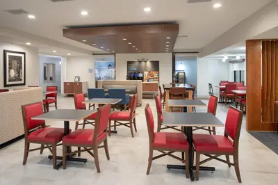 a dining room with tables and red chairs at Holiday Inn Express Hotel & Suites Longmont by IHG in Longmont