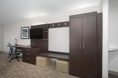 a room with a desk and a tv and a cabinet at Holiday Inn Express Hotel & Suites Longmont by IHG in Longmont