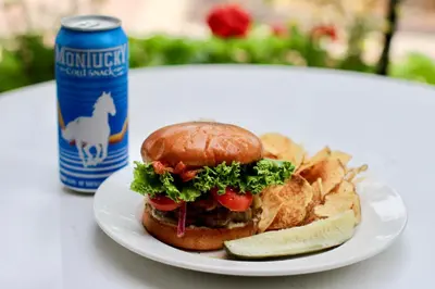 a sandwich and chips on a plate with a can of beer at The Armstrong Hotel in Fort Collins
