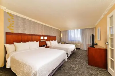 a hotel room with two beds and a flat screen tv at Courtyard by Marriott Denver Cherry Creek in Denver