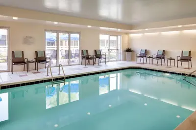a swimming pool with chairs and tables in a building at Fairfield Inn by Marriott Loveland Fort Collins in Loveland