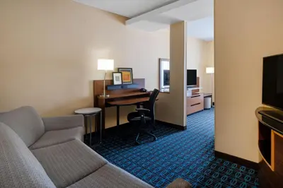 a room with a couch and a desk in a hotel room at Fairfield Inn & Suites by Marriott Denver Aurora/Medical Center in Aurora