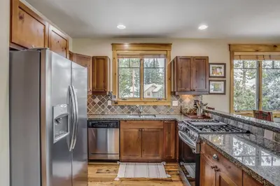 a kitchen with wooden cabinets and a stainless steel refrigerator at East Keystone by Vail Resorts in Keystone