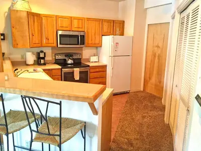 a kitchen with wooden cabinets and a white refrigerator at Condo Right On Main Street By Daniel in Frisco
