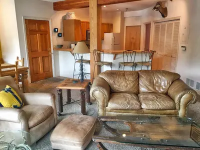 a living room with a leather couch and a table at Condo Right On Main Street By Daniel in Frisco