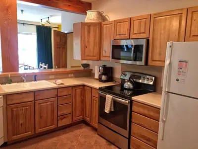 a kitchen with wooden cabinets and a white refrigerator at Condo Right On Main Street By Daniel in Frisco