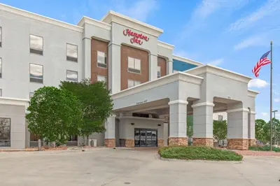 an office building with an american flag in front of it at Hampton Inn Denver Northeast-Brighton in Brighton