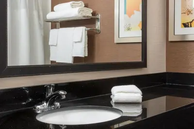 a bathroom with a sink and a mirror and towels at Fairfield Inn & Suites Greeley in Greeley