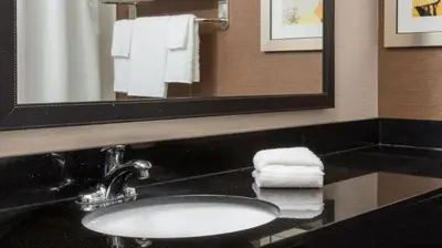 a bathroom with a sink and a mirror and towels at Fairfield Inn & Suites Greeley in Greeley