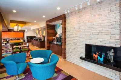 a living room with a fireplace and blue chairs at Fairfield Inn & Suites Greeley in Greeley