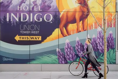 a woman walking a bike in front of a sign at Hotel Indigo Denver Downtown - Union Station by IHG in Denver