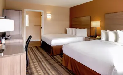 a hotel room with two beds and a desk at Boulder University Inn in Boulder