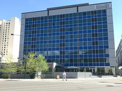 a person walking in front of a large glass building at Staybridge Suites Denver Downtown by IHG in Denver