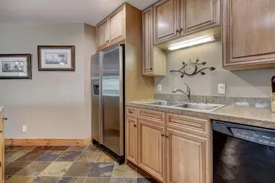 a kitchen with wooden cabinets and a stainless steel refrigerator at Timbers & Lone Eagle by Vail Resorts in Keystone