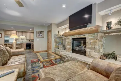 a living room with a stone fireplace and a tv at Timbers & Lone Eagle by Vail Resorts in Keystone
