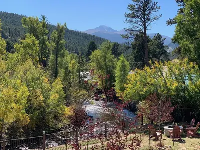 a river in the middle of a forest with trees at The Landing at Estes Park in Estes Park