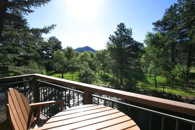 a wooden bench on a deck with a view of trees at The Landing at Estes Park in Estes Park